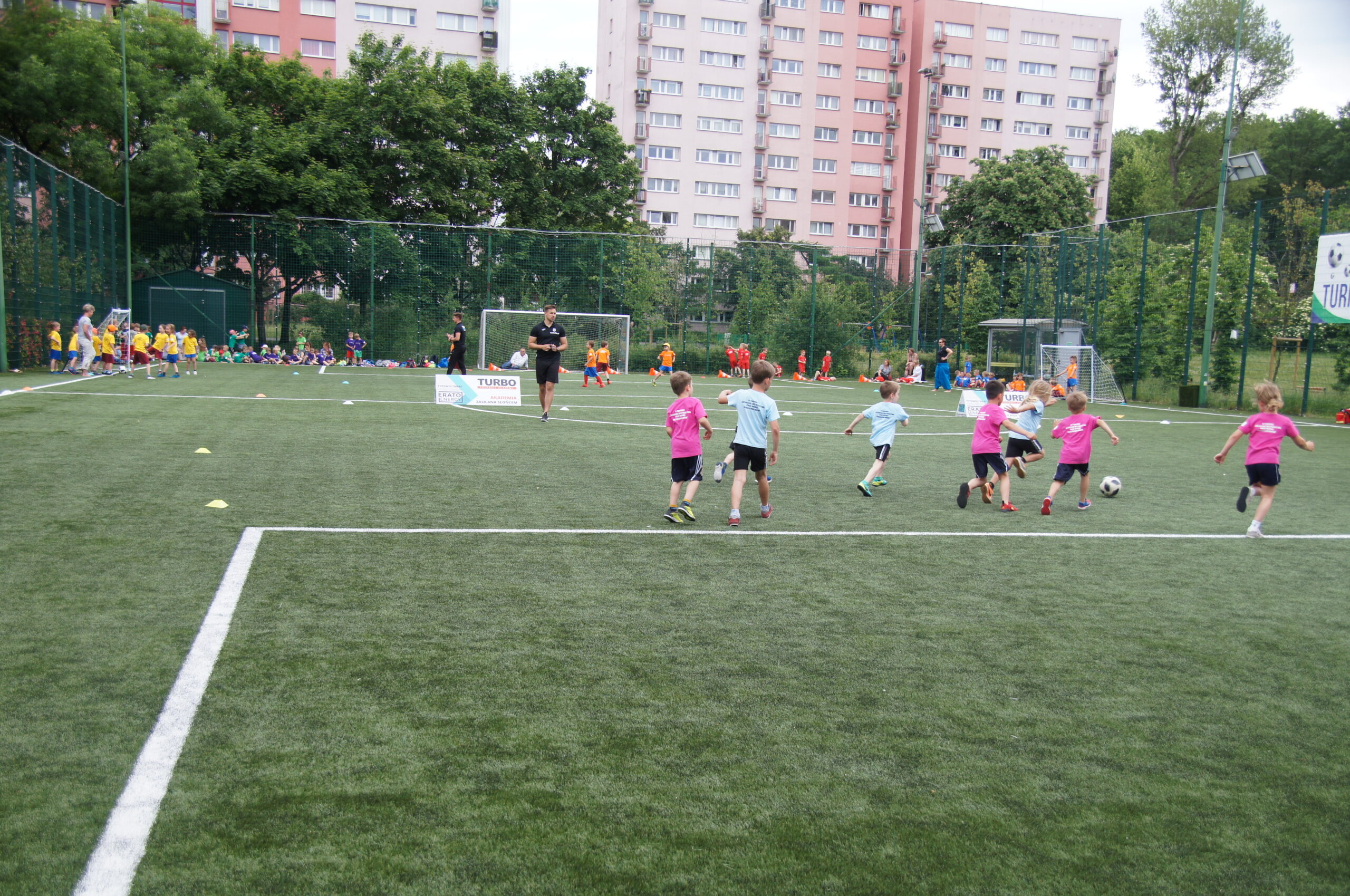 Młodzi zawodnicy, przedszkolaki grają na zielonej murawie boiska zewnętrznego Syrenka.