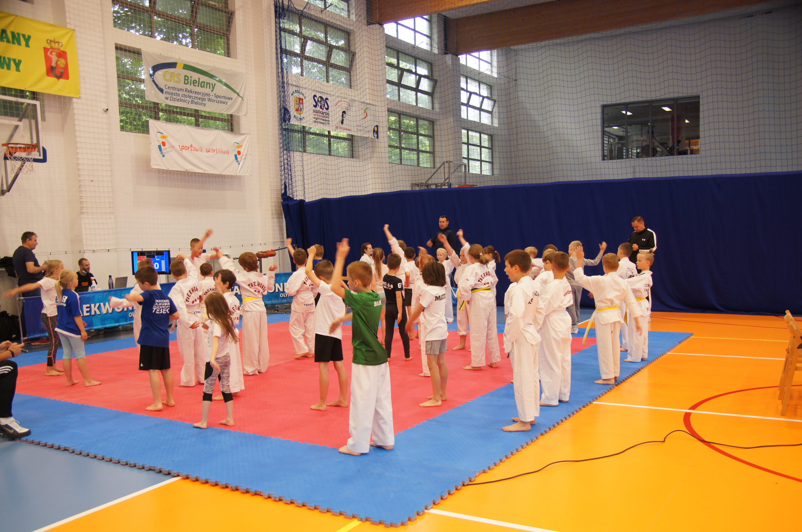 Duża ilość dzieci przygotowujące się do zawodów na hali sportowej.