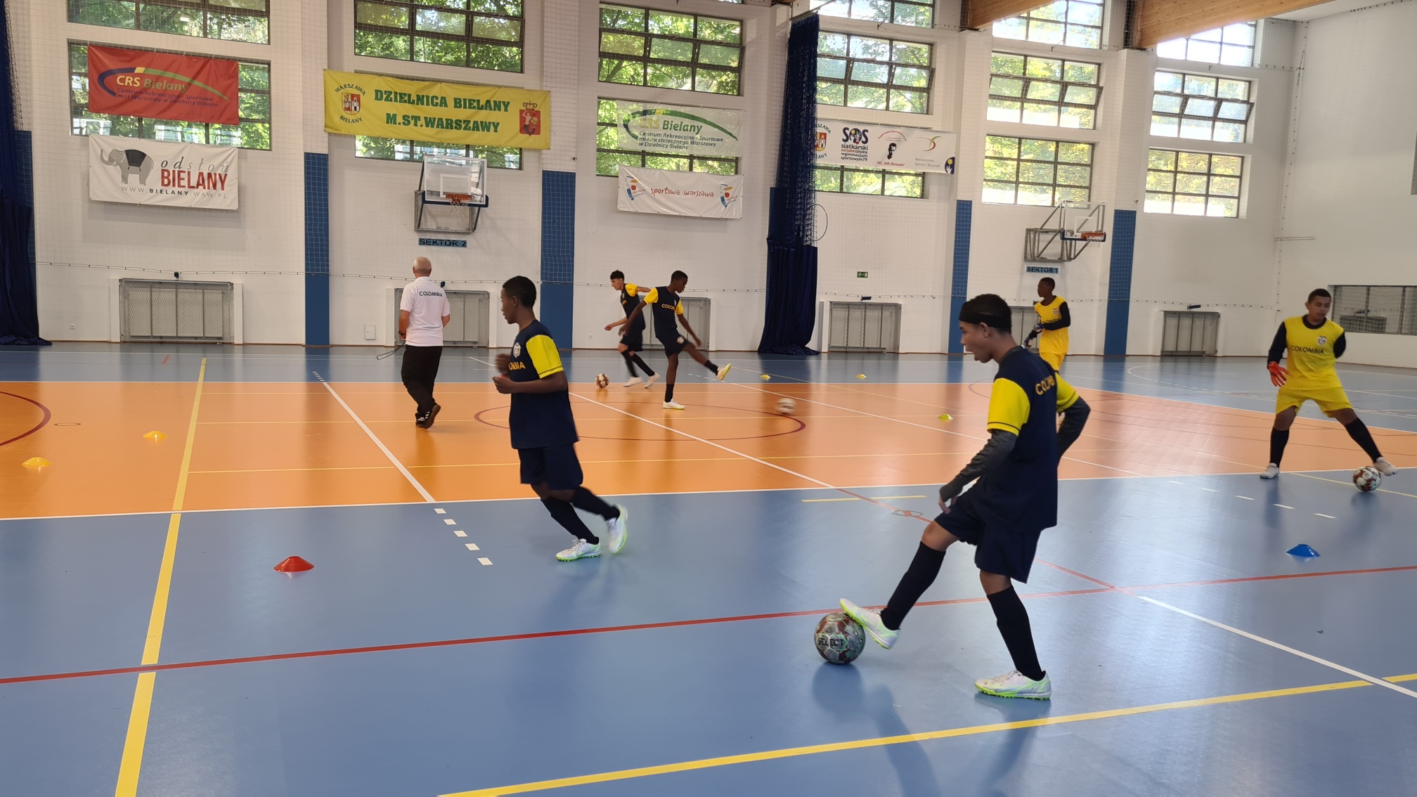 Młodzi chłopcy z Kolumbii grający w piłkę nożną na hali sportowej.